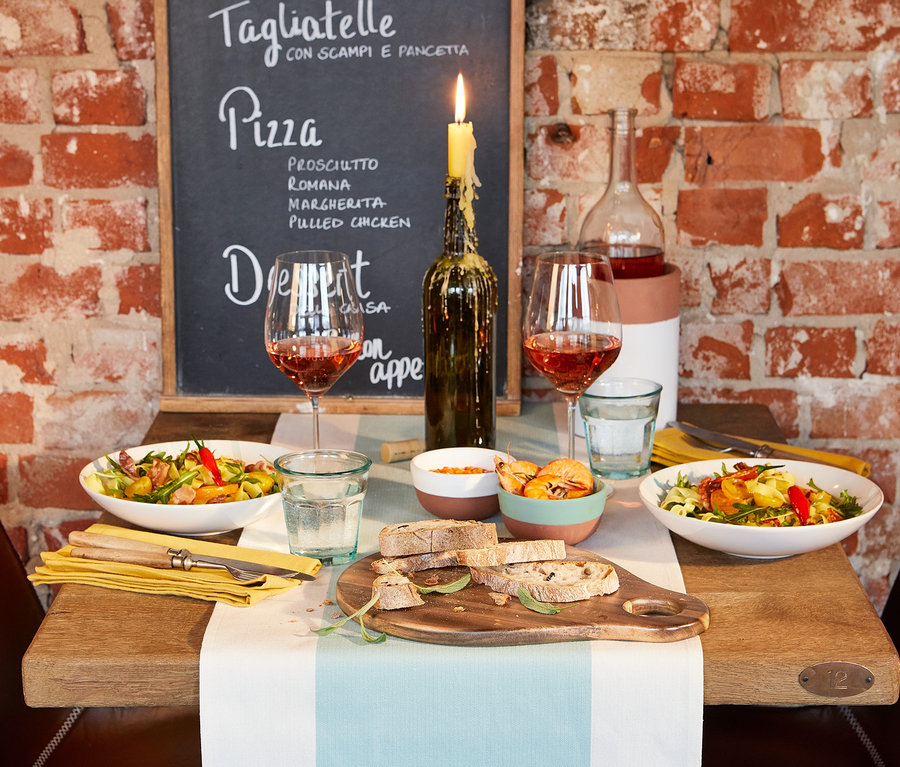 Gedeckter Tisch mit 2 tiefen Tellern, Servierbrett, 2 kleinen Schälchen und Tischläufer.