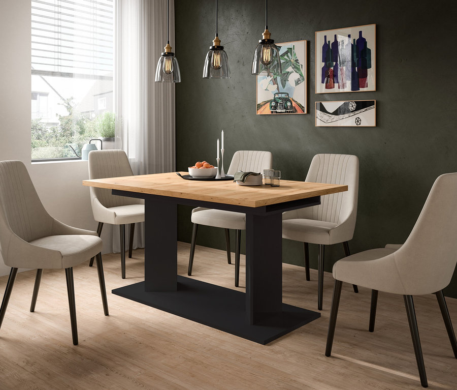 Ein modernes Esszimmer mit hellem Holztisch, schwarzem Untergestell und vier beigen Polsterstühlen. Drei Pendelleuchten hängen über dem Tisch, auf dem eine Schale Orangen und Kerzen stehen. Links ist ein Fenster, an der dunklen Wand hängt abstrakte Kunst.