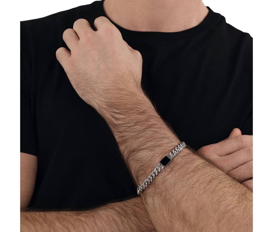 Nahaufnahme eines Mannes, der ein Amor Unisex-Armschmuck mit Anhänger trägt.