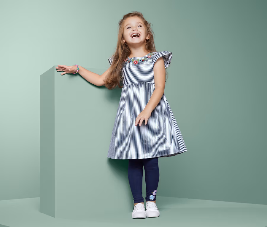 Mädchen posiert in einem Kleid mit Stickerei.