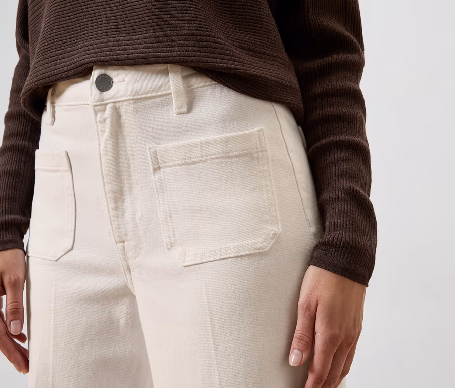 Person trägt hellbeige Wide Leg Jeans – Fit „Viki“ mit aufgesetzten Fronttaschen und ein dunkelbraunes, geripptes Langarmshirt.