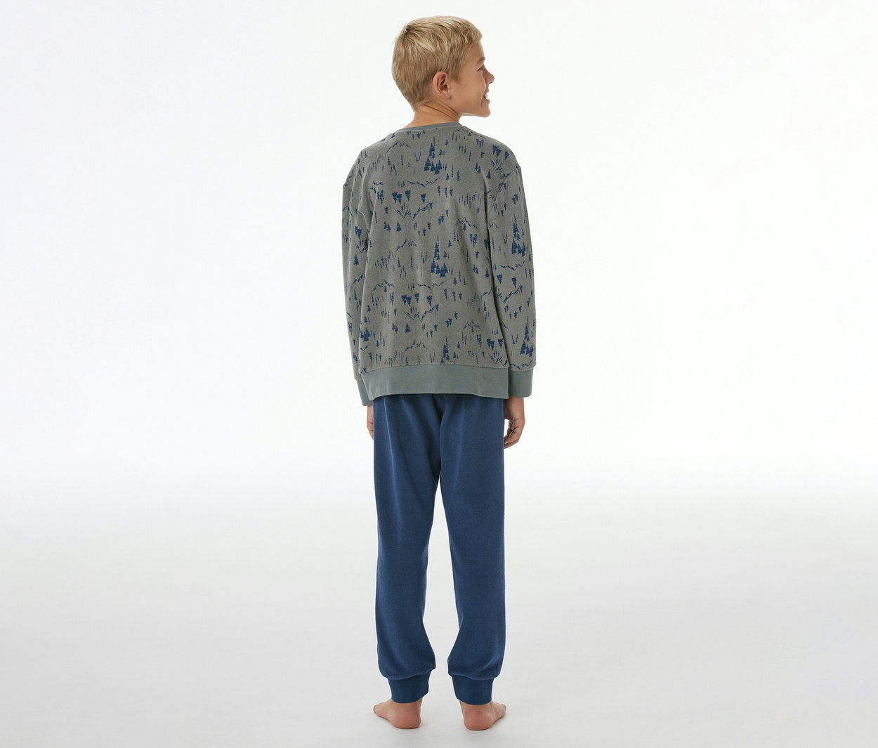 Junge von hinten in grauem SCHIESSER Kinder-Pyjama mit blauem Baummuster und blauer Hose mit Bündchen.