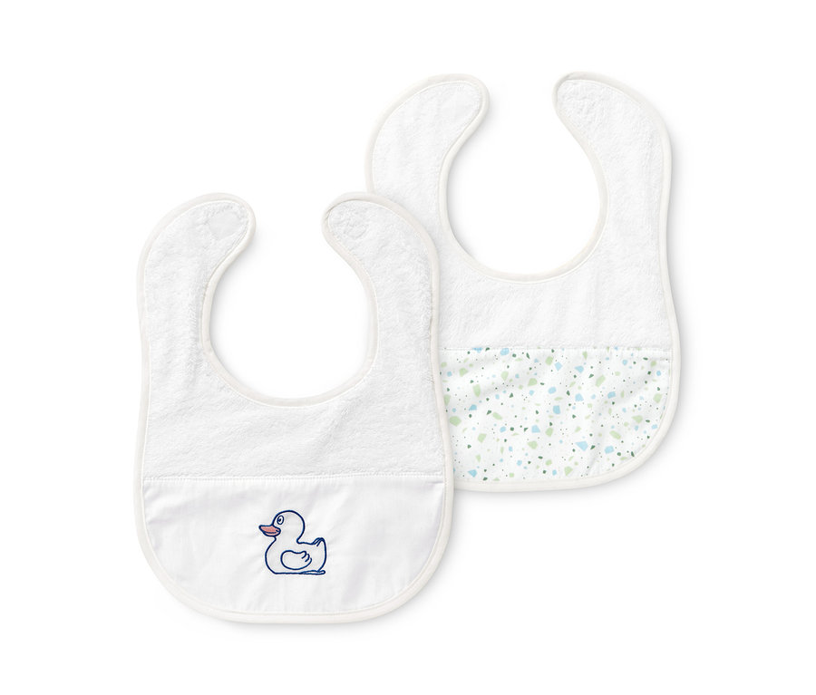 Zwei Baby-Lätzchen liegen auf weißem Grund.