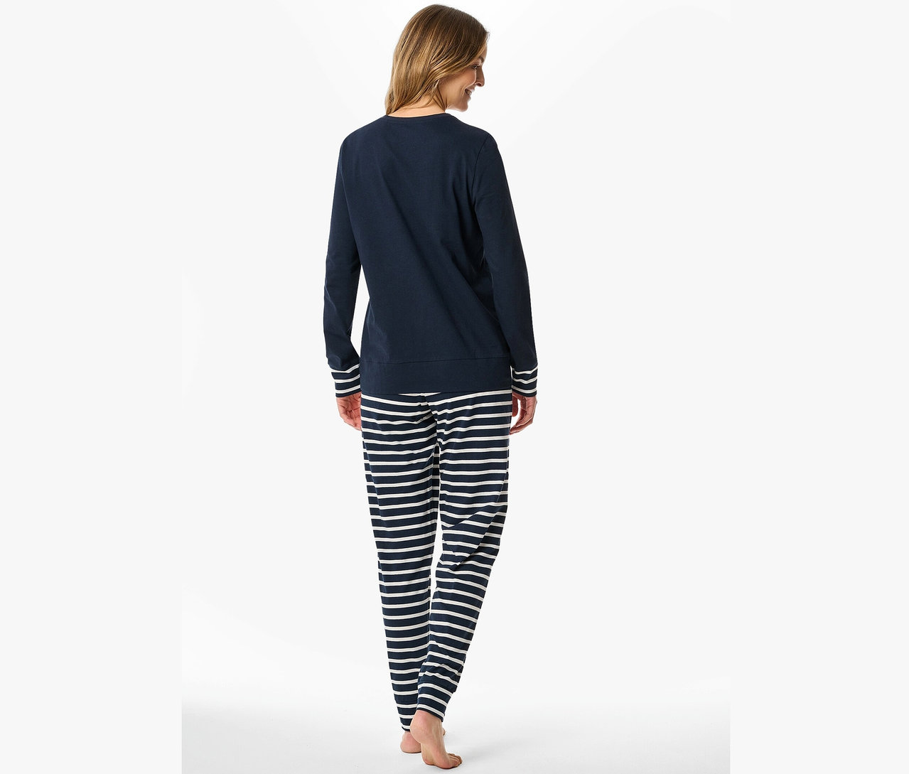 Frau von hinten trägt marineblauen Pyjama mit weißen Streifen.