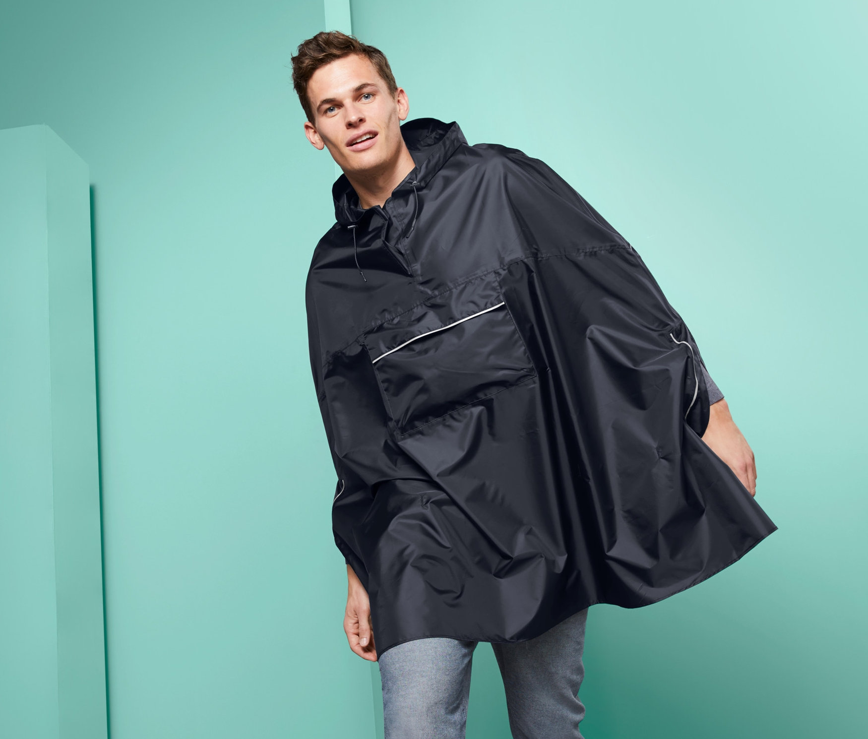 Mann posiert in einem schwarzen Unisex-Regenponcho.