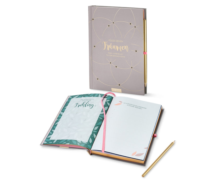Zwei offene graue Notizbücher »Folge deinen Träumen« und ein goldener Stift.