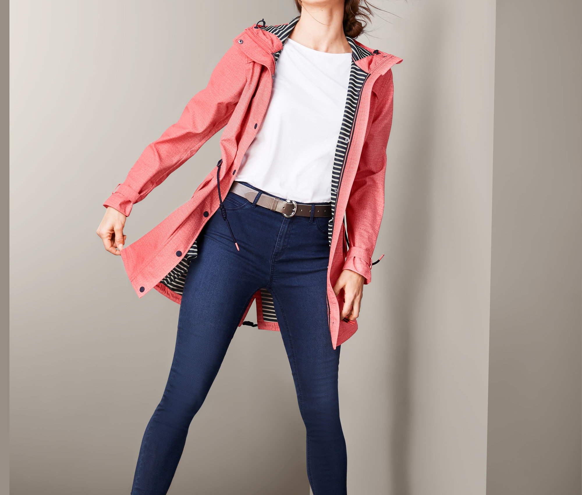 Frau posiert in Softshellmantel, Jeans und braunen Stiefeln.