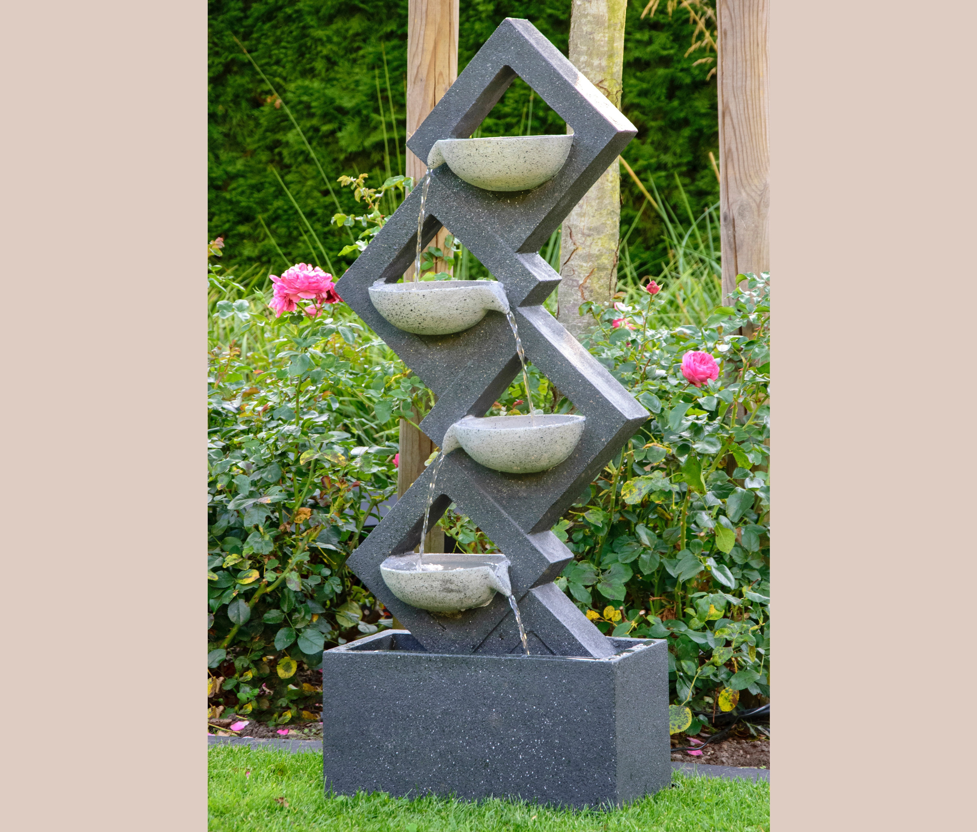 Dobar Gartenbrunnen mit 4 Schalen und LEDs in einem blühenden Garten.