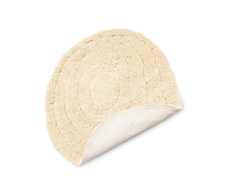 Beige Badematte in organischer Form, teilweise aufgerollt, wobei die Unterseite sichtbar ist.