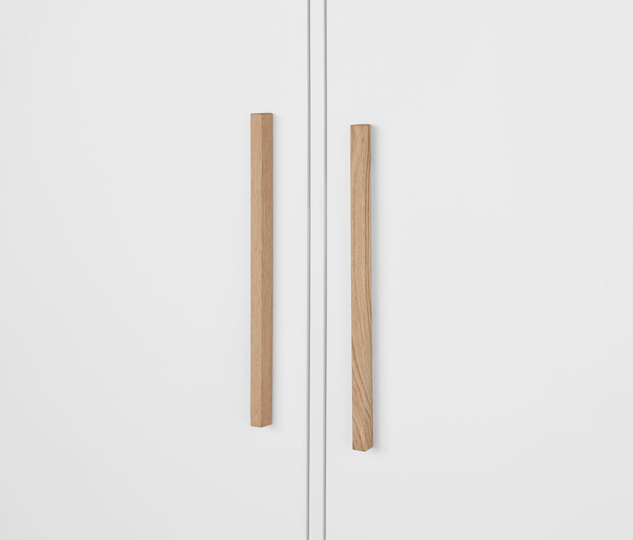 Detailansicht eines weißen Kleiderschranks »Eklund« mit Schubladen, der Holzgriffe zeigt.