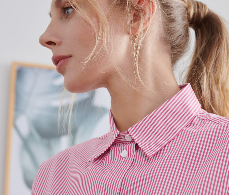 Detail einer Frau, die eine gestreifte Hemdbluse trägt.