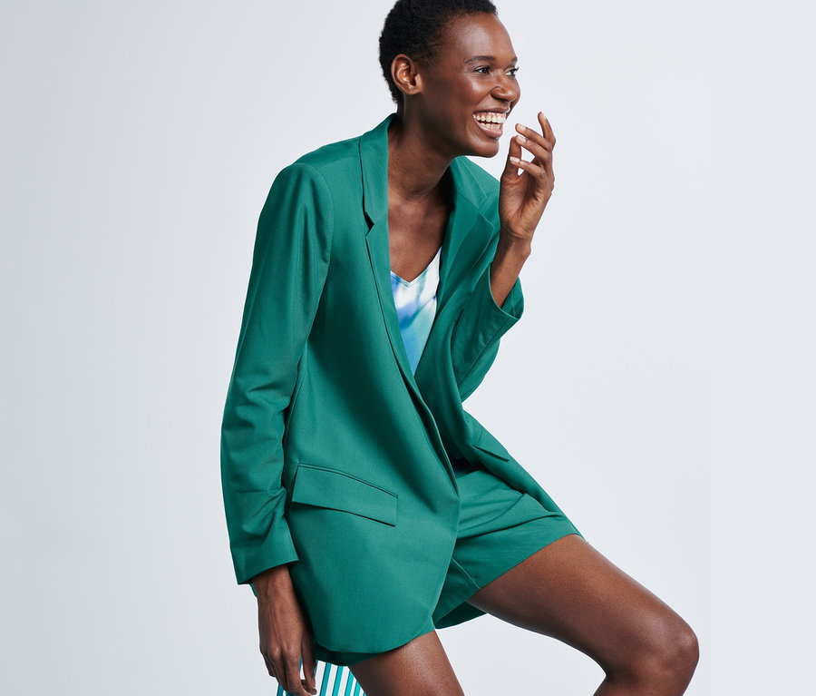 Lächelnde Frau posiert im Longblazer.