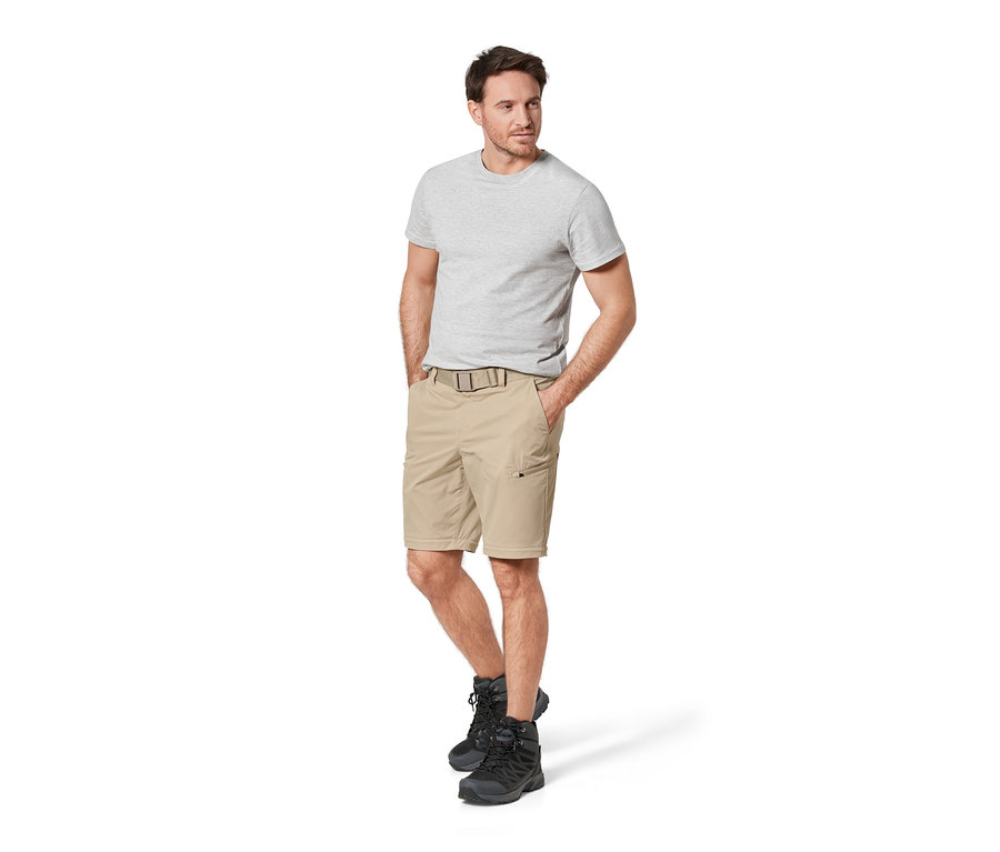 Mann steht mit Händen in den Taschen einer beigen 2-in-1-Funktionshose.