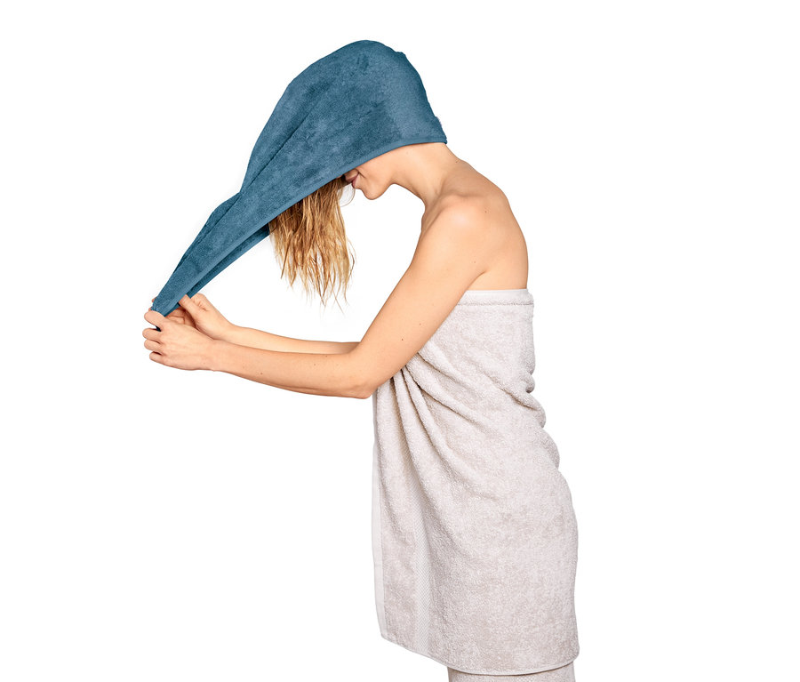 Frau legt ein blaues Turban-Handtuch um ihren Kopf.
