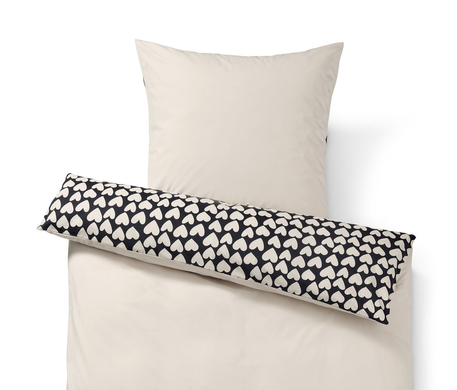 Beige Bettwäsche und Kissen mit schwarzem Kissenbezug mit weißen Herzen.