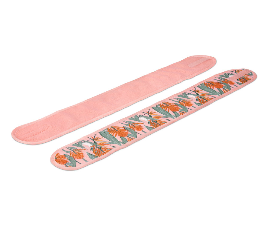 Zwei Kosmetik-Stirnbänder, eines rosa und eines mit tropischem Muster.