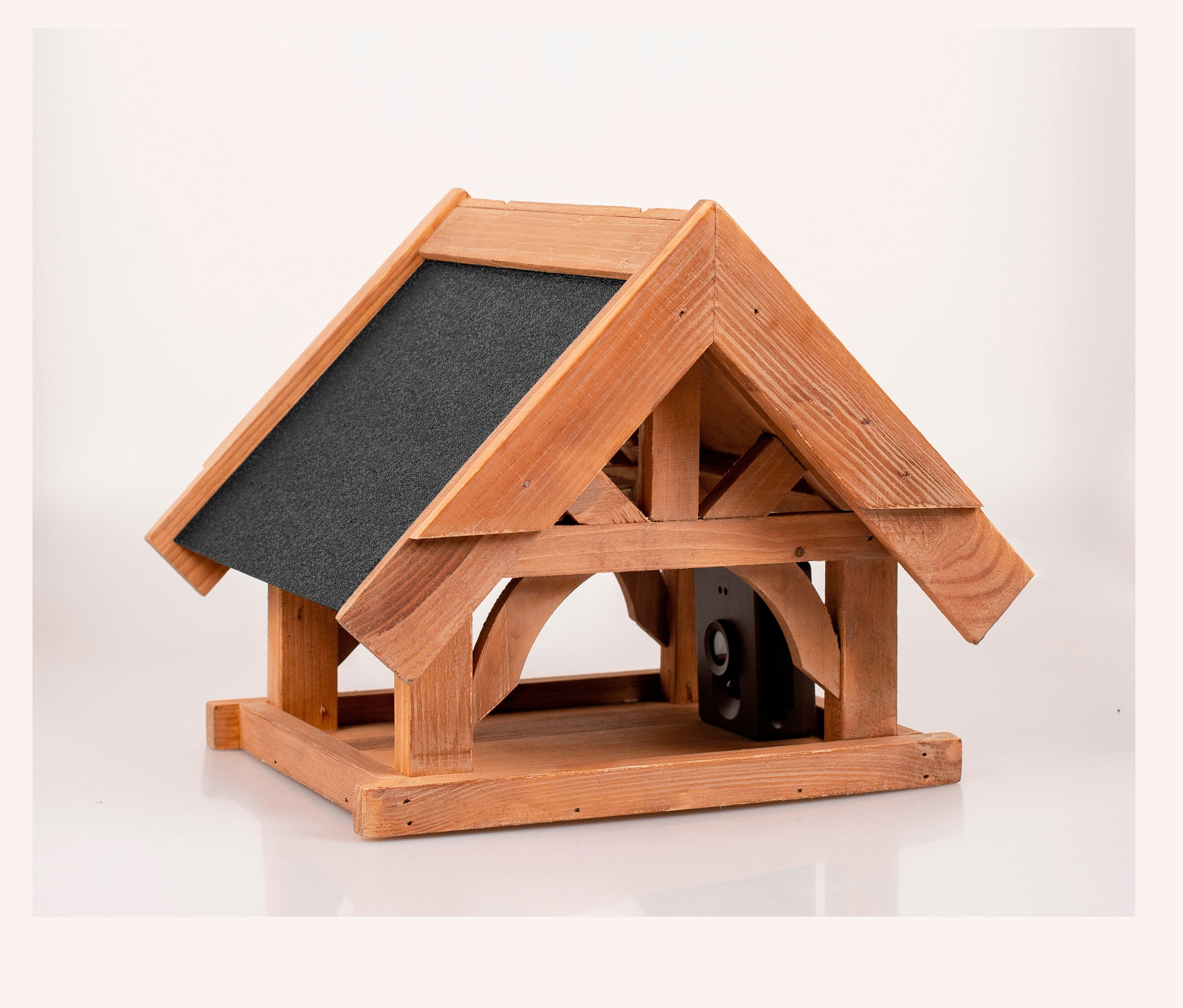 Nahaufnahme eines Vogelhauses mit Kamera, aus Holz gefertigt und mit einem grauen Dach versehen.