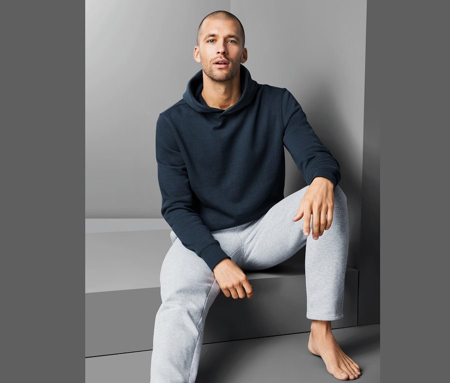 Mann sitzt und trägt einen Hoodie.