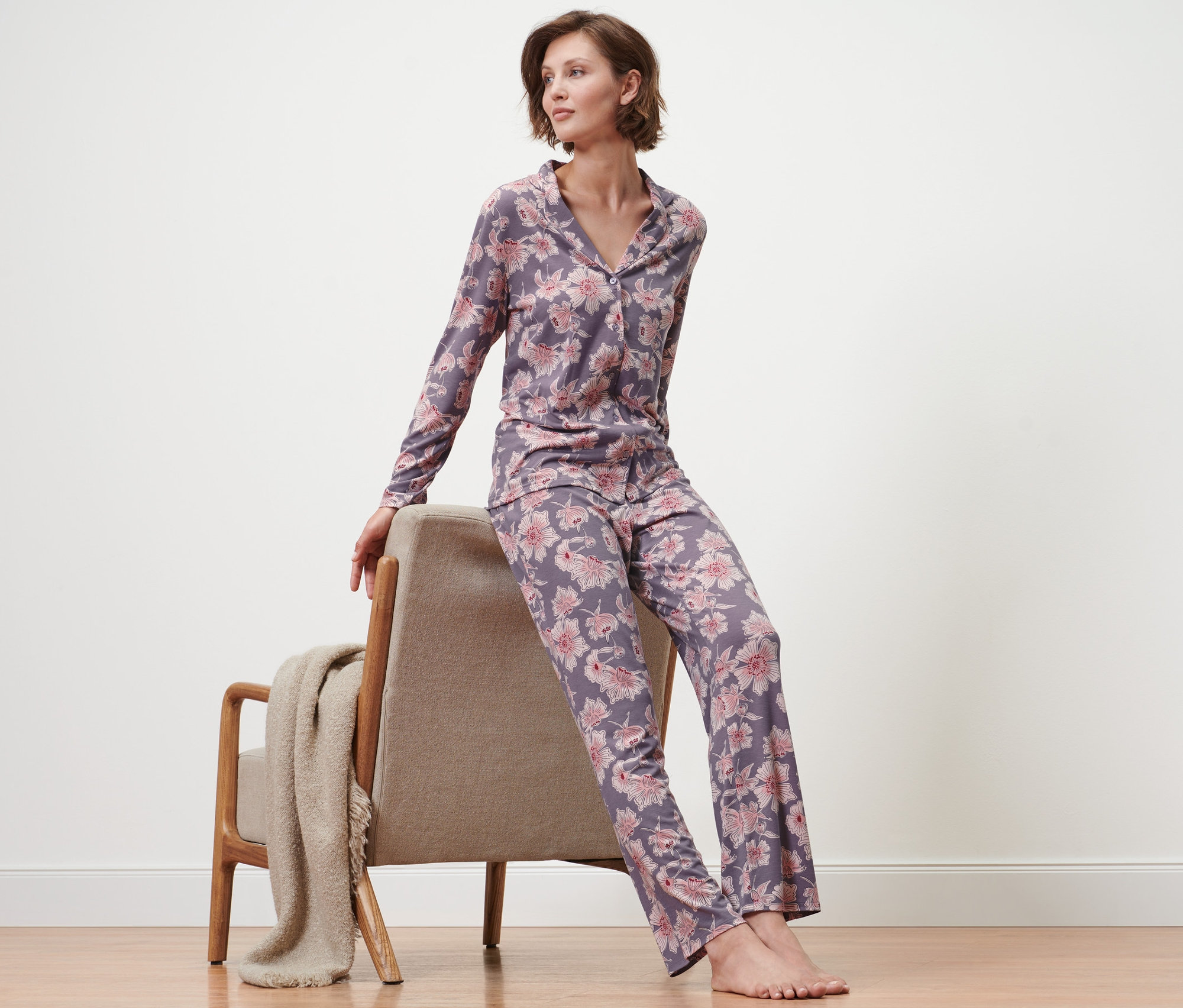 Frau sitzt auf Sessel und trägt einen Pyjama mit Blumenmuster.