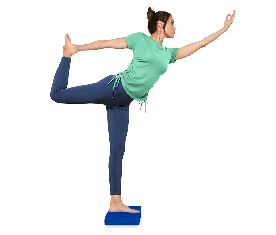 Frau steht in Tänzerpose auf Balance-Pad.