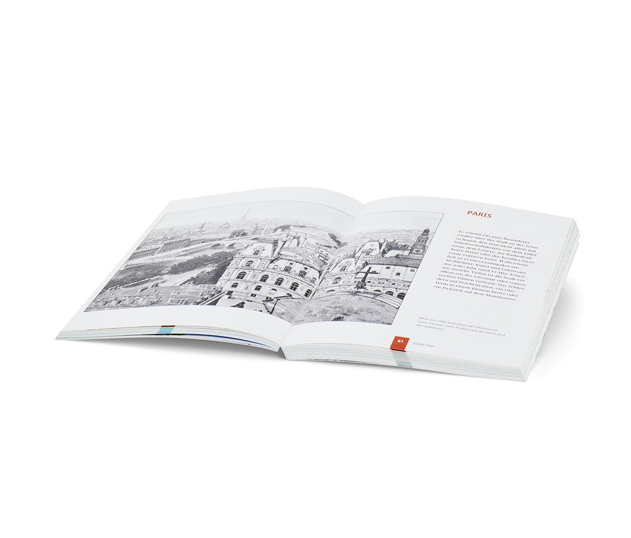 Offenes Buch mit Schwarzweißbild von Paris. Buch: Landkarten-Rätselbuch »Weltreise«.