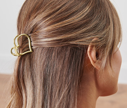 Rückansicht einer Frau mit braunem Haar, das mit einer Haarklemme im Herzdesign befestigt ist.
