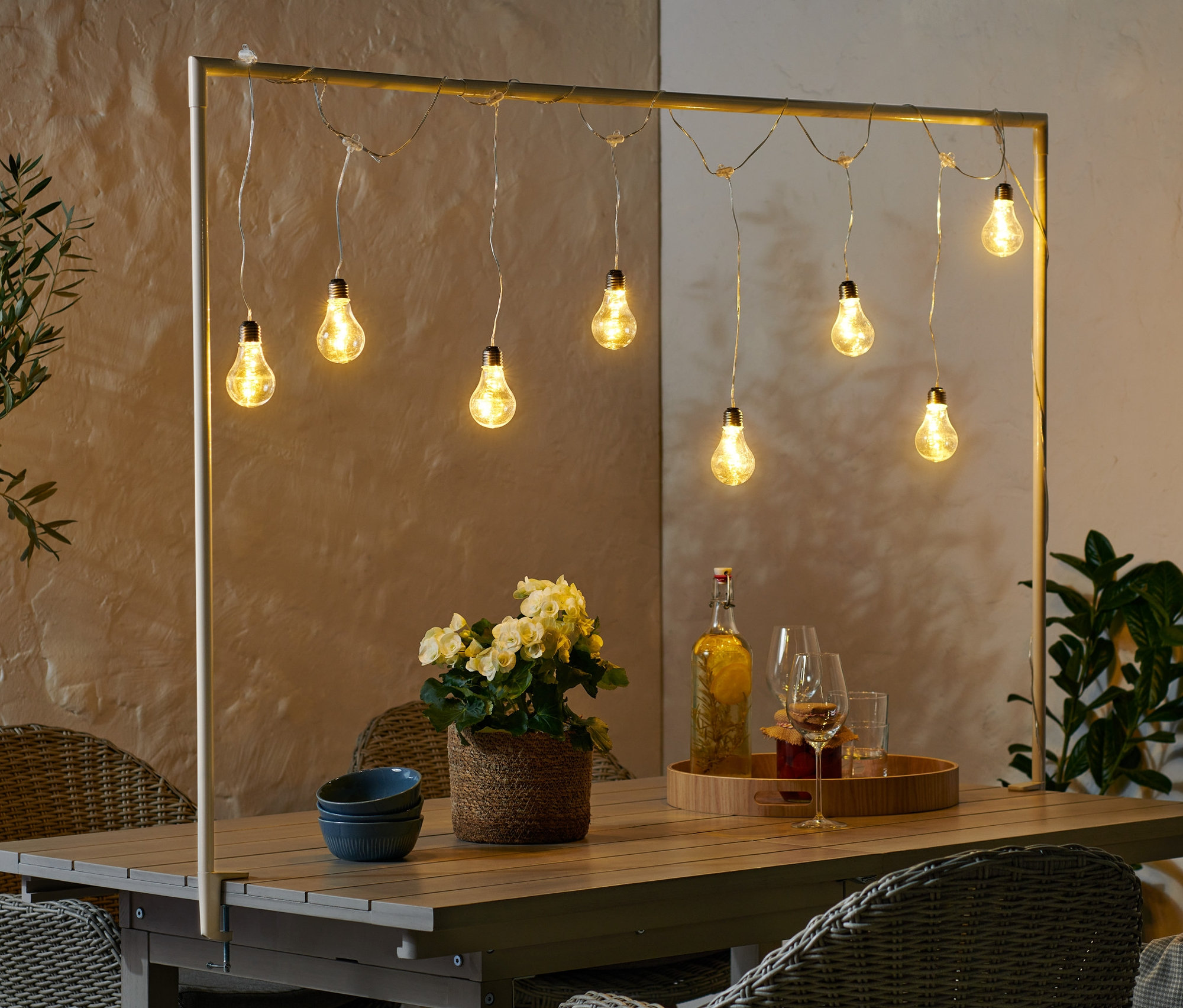 Deko-Tischstange inkl. LED-Lichterkette beleuchtet Tisch mit Blumen, Getränken und blauen Schalen.