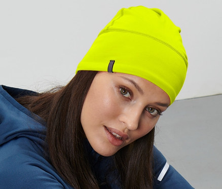 Frau sitzt auf dem Boden und trägt eine neongelbe Thermomütze.