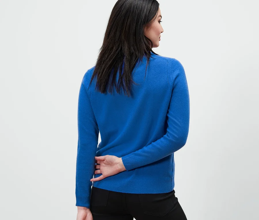 Frau steht mit dem Rücken zur Kamera und trägt einen kobaltblauen Feinstrickpullover mit Cashmere.