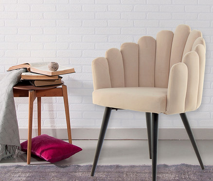 Ein cremefarbener Kayoom Stuhl "Jeane" steht auf einem Teppich vor einer weißen Ziegelwand.