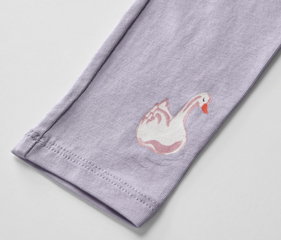 Detailaufnahme einer lila Kinderleggings mit Schwanenmotiv.