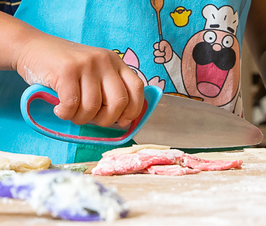 Kind schneidet Teig mit einem Messer aus dem Chefclub Koch-Set.