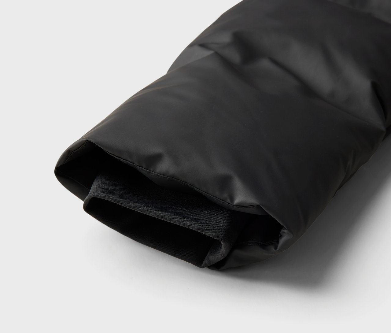 Detailansicht eines Ärmels einer schwarzen Daunenjacke.