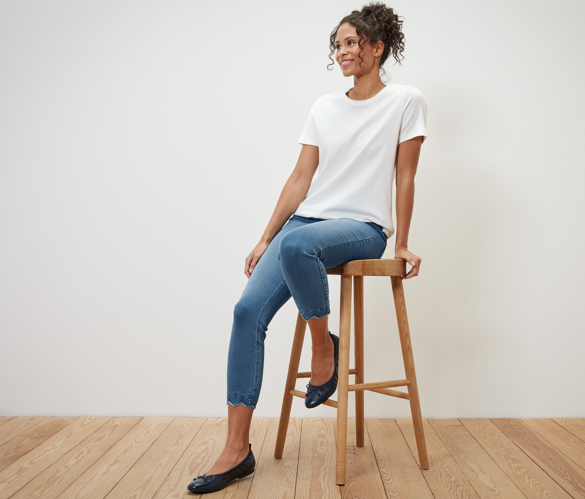 Frau sitzt auf einem Hocker und trägt eine 7/8-Treggings mit Lochstickerei.