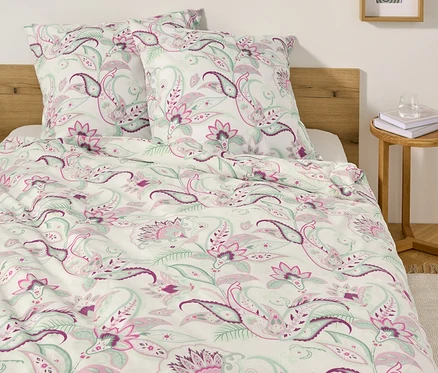 Bett mit weißer Renforcé-Bettwäsche mit Paisley-Muster und zwei Kissen.