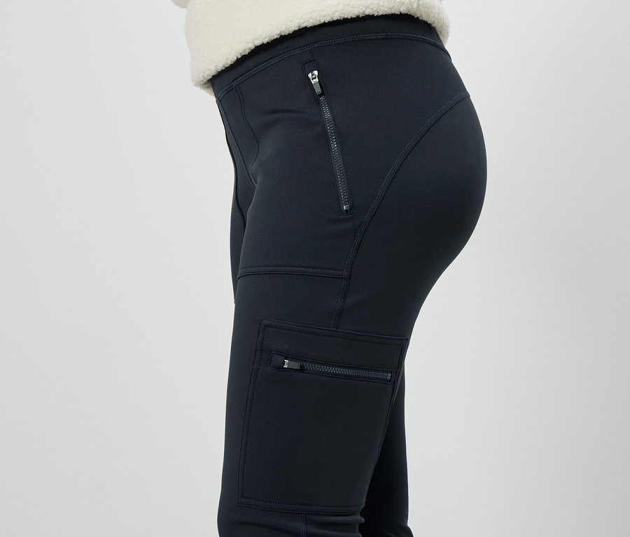 Seitenansicht einer Frau in schwarzen Hosen mit Reißverschlusstaschen.