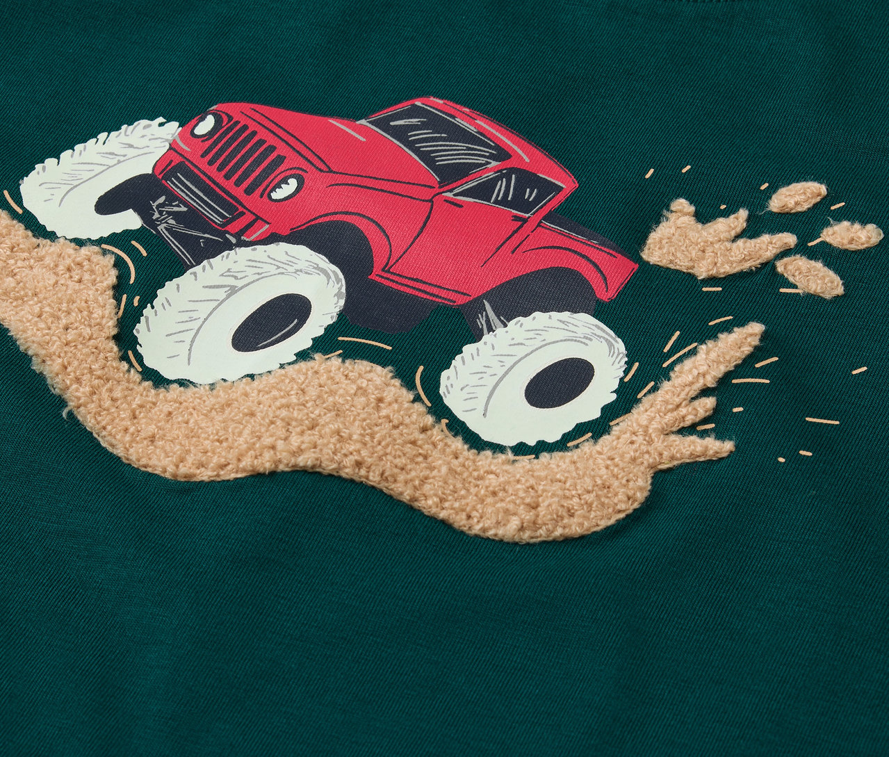 Detailaufnahme eines grünen Langarmshirts mit einem roten Truck-Aufdruck.