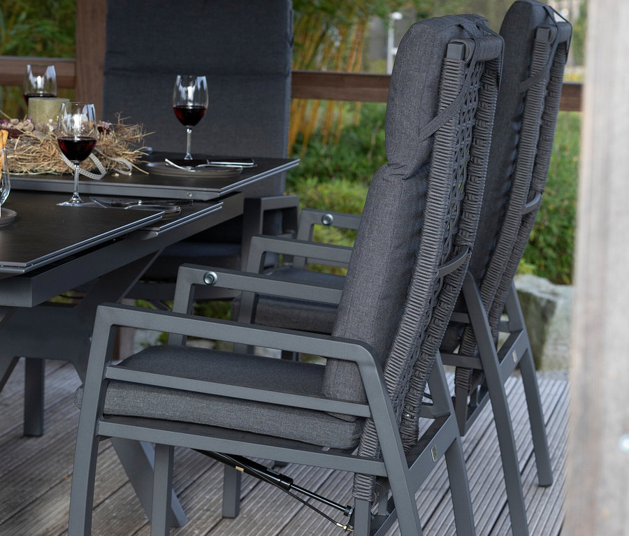 Zwei graue deVries Stühle mit Seil stehen an einem Tisch mit Weingläsern.