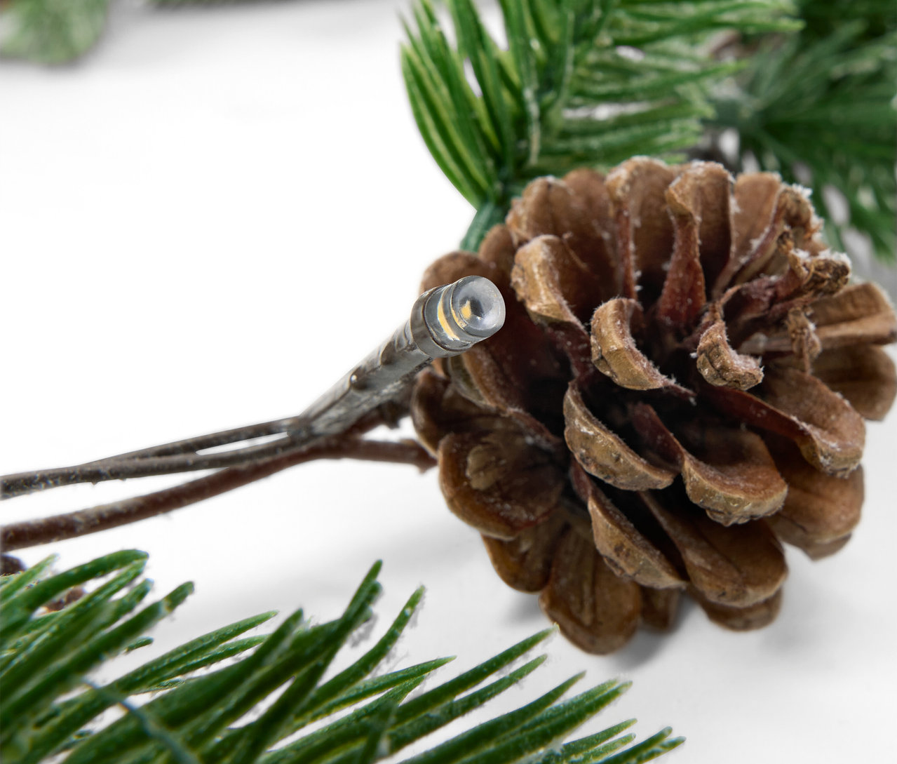 Detail einer Lichterkette mit Zapfen und Tannenzweigen.