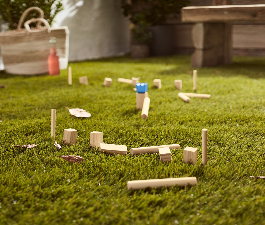 Mini-Kubb-Spiel liegt auf dem Rasen.