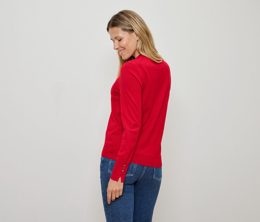 Frau mit rotem Pullover und blauen Jeans, die nach unten schaut.