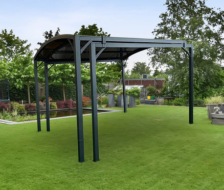 Grüner Rasen mit Leco Pergola und Sitzbereich im Hintergrund.