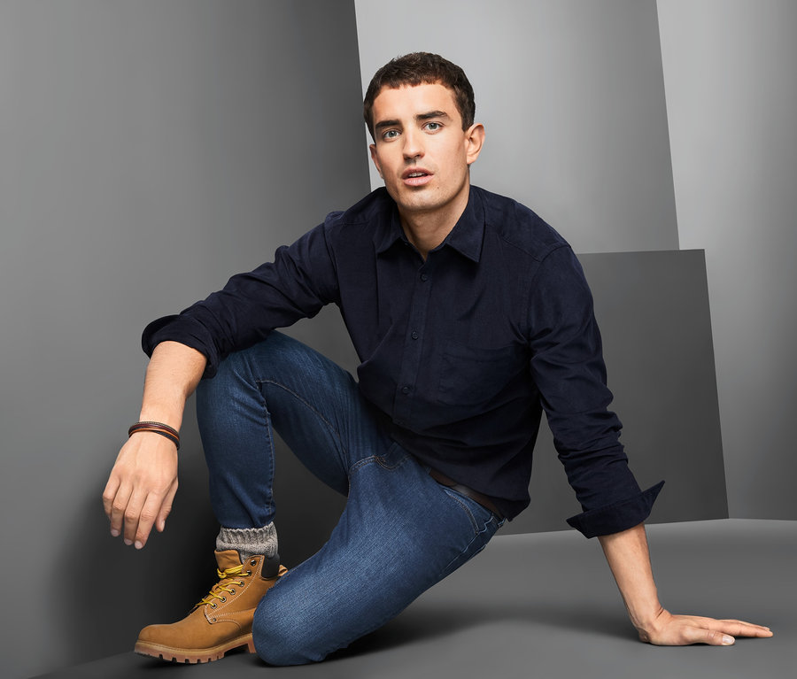 Mann kniet in blauem Cordhemd am Boden.