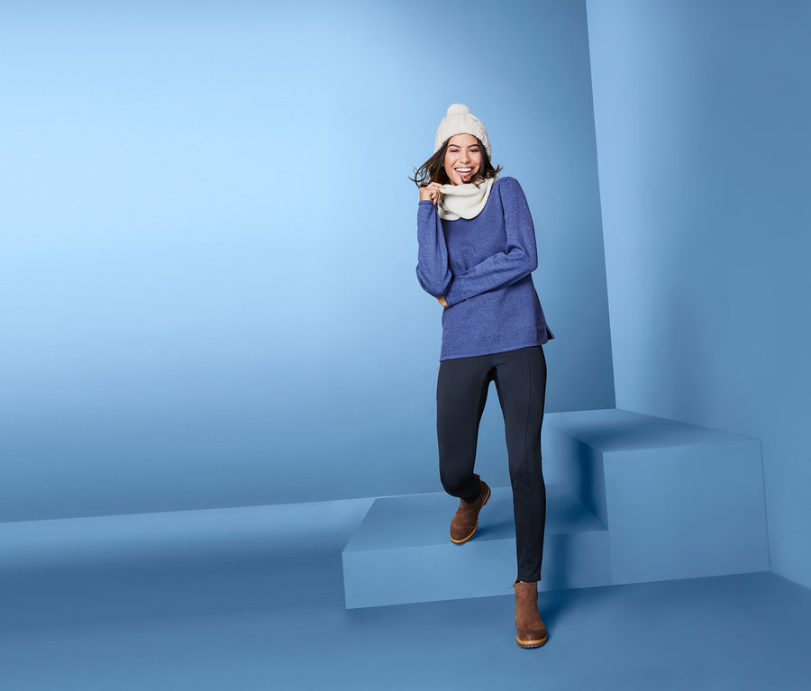 Frau in blauem Pullover, Thermotight und Wintermütze steigt Stufen hinunter.