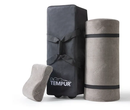 Graues TEMPUR® Reiseset, bestehend aus einer Tragetasche, einer zusammengerollten Matratze und einem Lordosekissen.