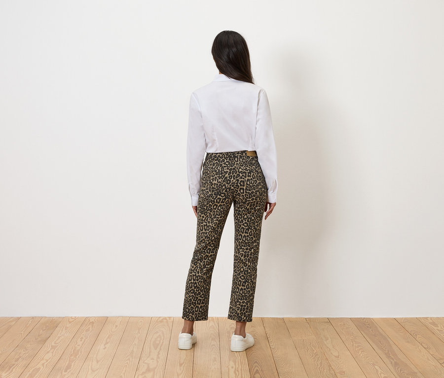 Rückansicht einer Frau mit weißem Hemd und Hose mit Leopardenmuster.