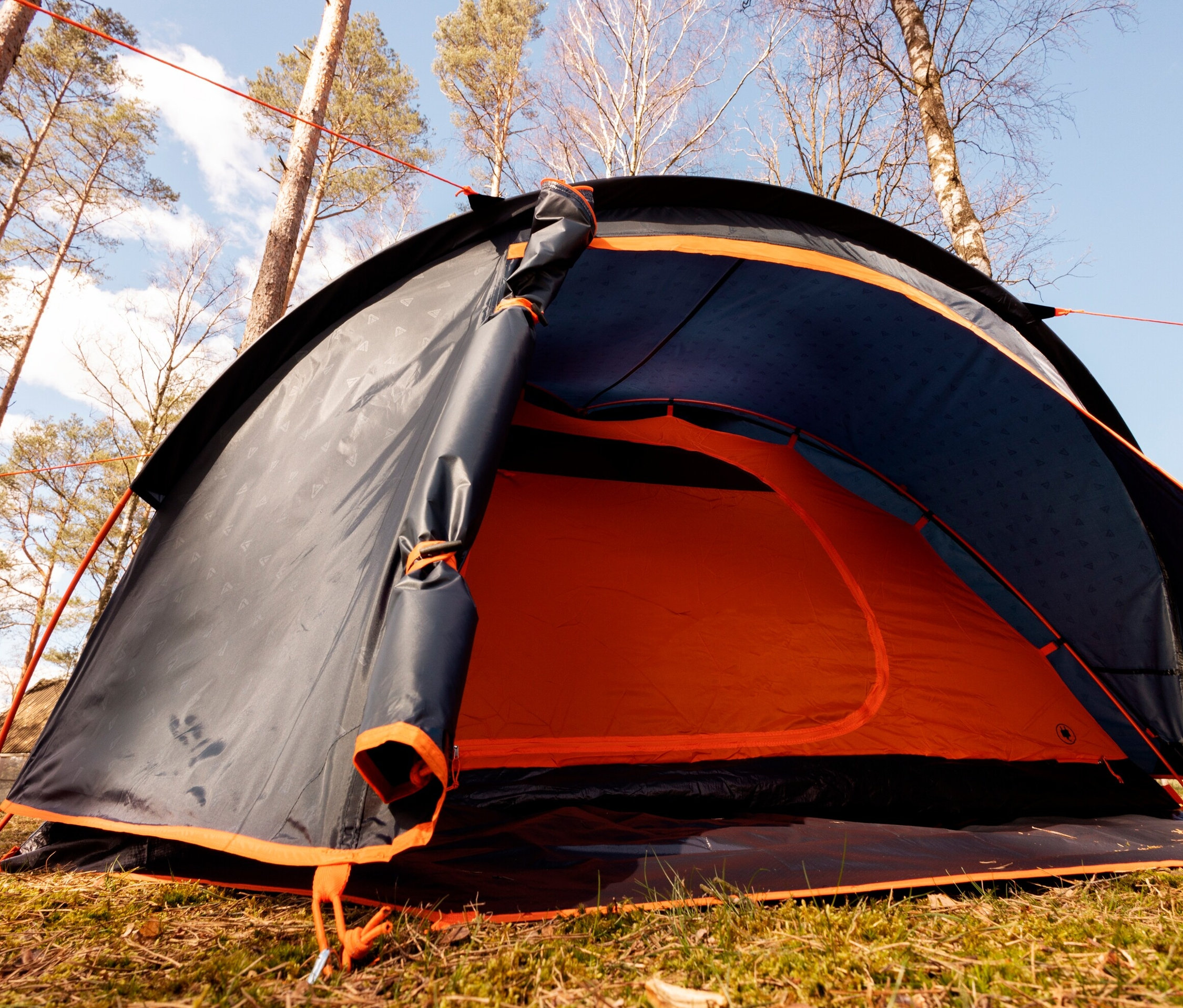 Nahaufnahme des Tambu 2-Personen-Kuppelzelts »HAIKA 2», aufgebaut auf Gras mit offenem Eingang.