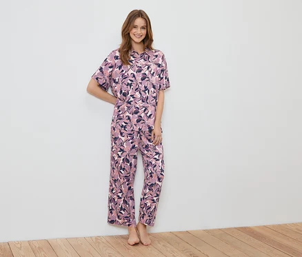 Eine Frau steht und trägt einen Pyjama mit Blumenmuster.