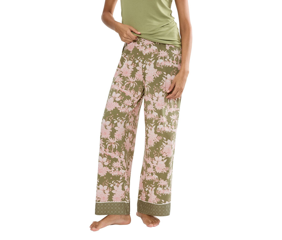 Frau trägt ein grünes Tanktop und eine olivgrüne Pyjamahose mit rosa Blumenmuster.