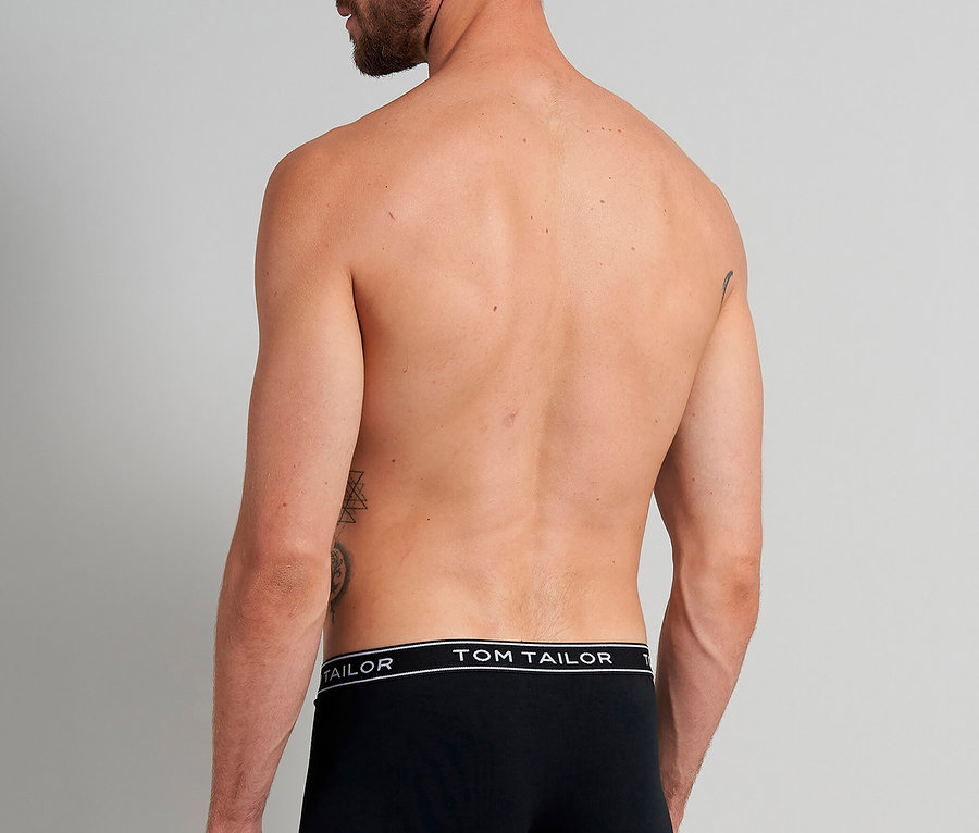 Mann von hinten, mit Tätowierungen, trägt schwarze Tom Tailor Boxershorts.